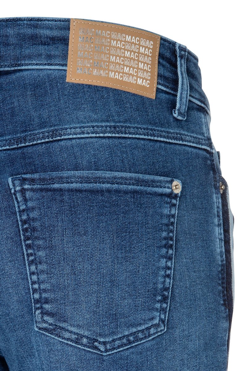 Close-up of blue jeans with a brand label on the back pocket against a white background