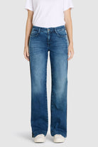 Person wearing blue jeans and a white shirt on a light gray background