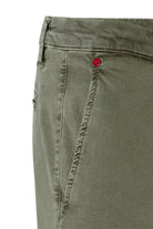 Close-up of green pants with a red button on a white background
