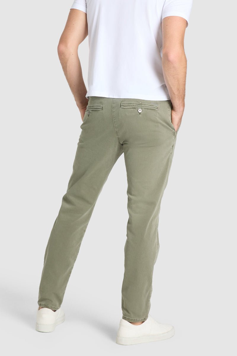 Person wearing olive green pants and a white shirt on a light gray background