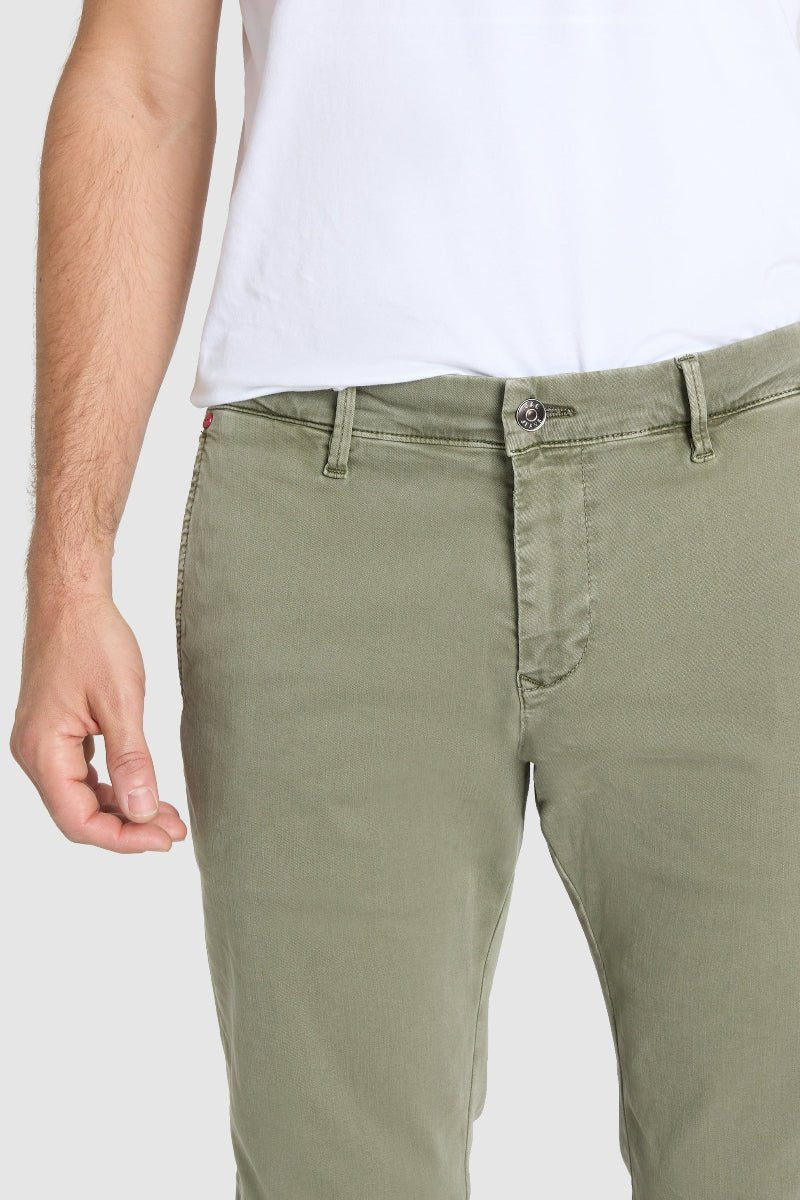 Person wearing olive green pants and a white shirt on a plain background