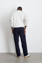 Person wearing a white sweatshirt and dark pants against a plain background