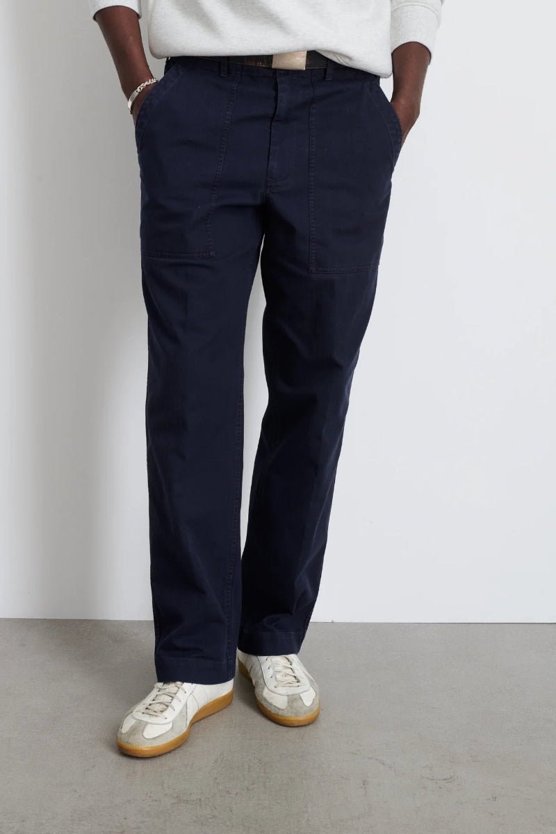 Person wearing navy pants and white shoes on a plain background