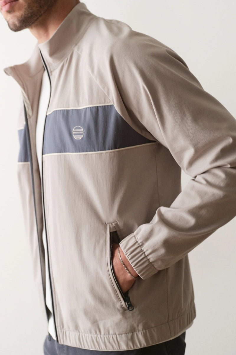 Beige jacket with a blue stripe on a plain background