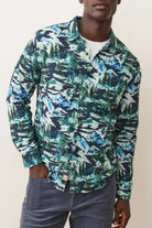 Man wearing a long-sleeve shirt with a blue and green abstract pattern on a plain background