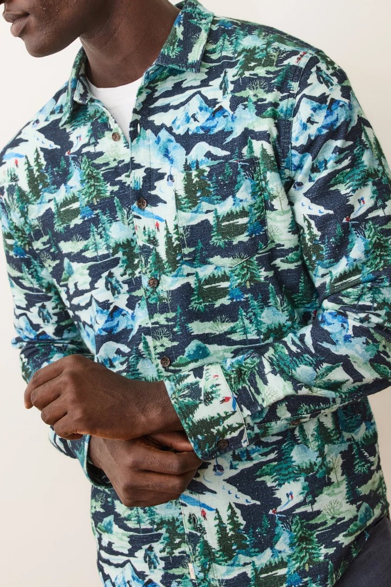 Person wearing a long-sleeve shirt with a nature-themed pattern on a plain background
