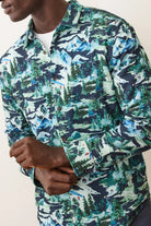 Person wearing a long-sleeve shirt with a nature-themed pattern on a plain background
