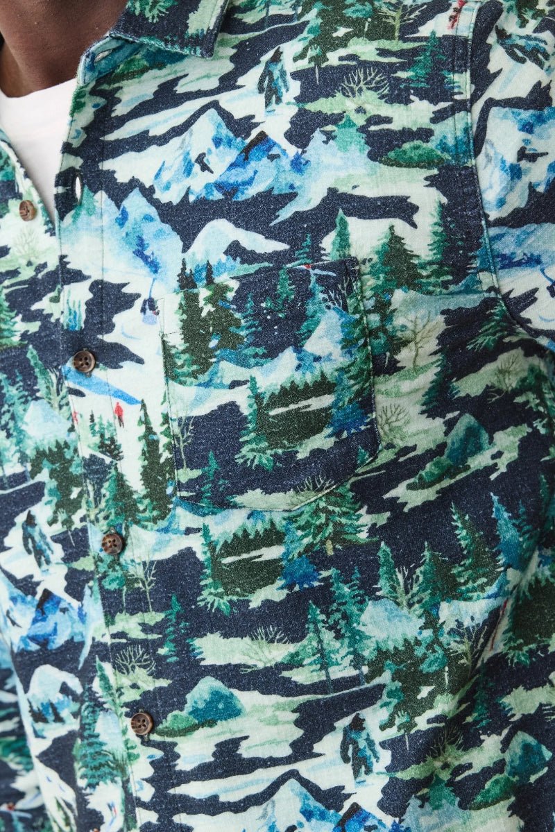 Close-up of a shirt with a nature-themed pattern featuring mountains and trees.