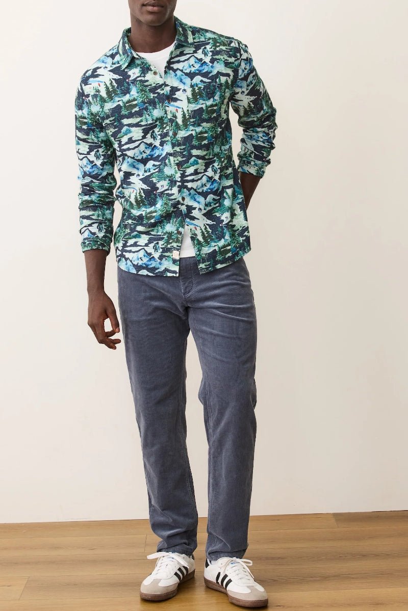 Person wearing a colorful patterned shirt and blue jeans on a plain background