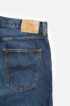 Close-up of a blue denim jeans back pocket with brand label on a white background