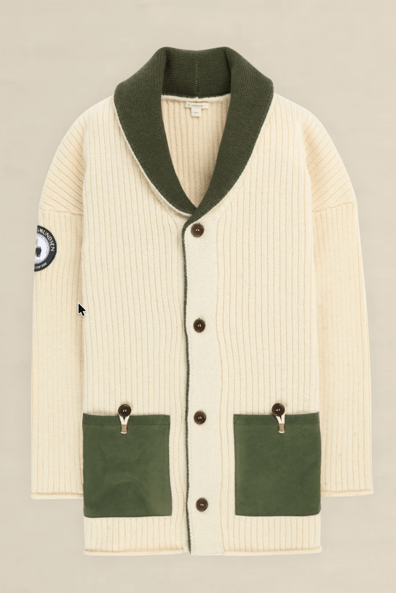 An off-white ribbed knit cardigan with an olive green shawl collar, green front pockets, and brown buttons, shown flat on a light beige background.