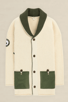 An off-white ribbed knit cardigan with an olive green shawl collar, green front pockets, and brown buttons, shown flat on a light beige background.