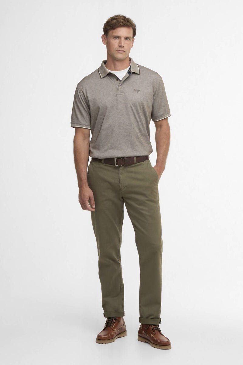 Man wearing a gray polo shirt and green pants on a white background