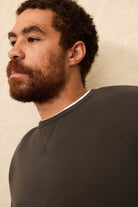 Man wearing a dark gray sweatshirt against a plain background