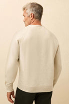 Man wearing a beige sweater against a beige background