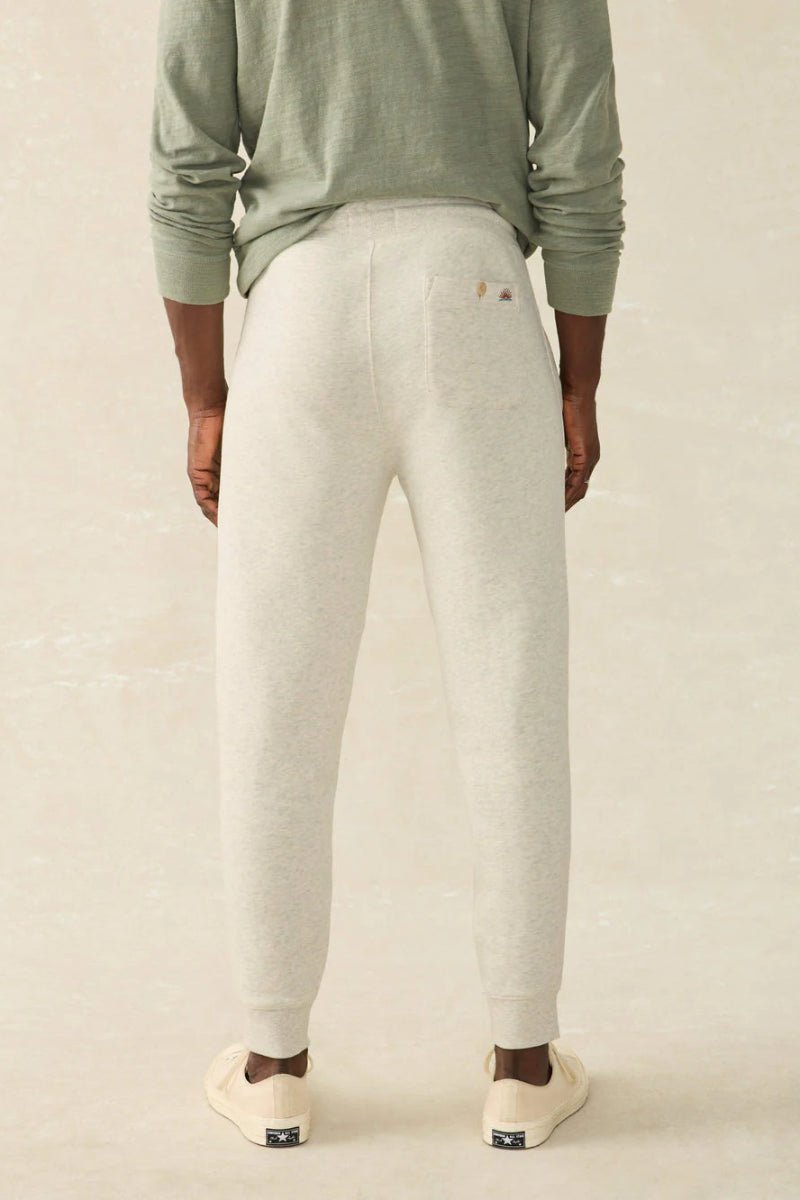 Person wearing light gray sweatpants and a green long-sleeve shirt on a beige background