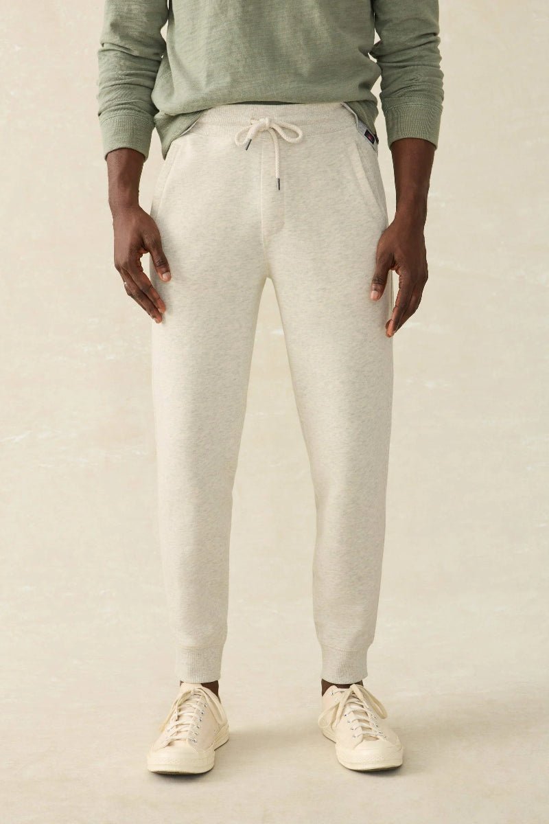 Person wearing a green sweatshirt and gray jogger pants on a beige background