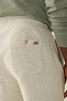 Light gray sweatpants with embroidered designs on the pocket, worn by a person.