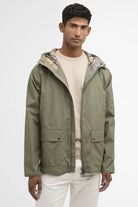 Man wearing a green jacket with a patterned hood on a white background