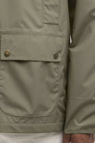 Close-up of a green jacket with pockets and buttons on a white background
