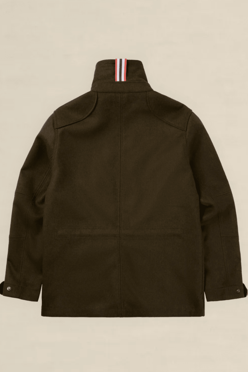 The back view of an olive green utility jacket with a high collar featuring a signature red, white, and blue striped ribbons detail, displayed on a neutral beige background.