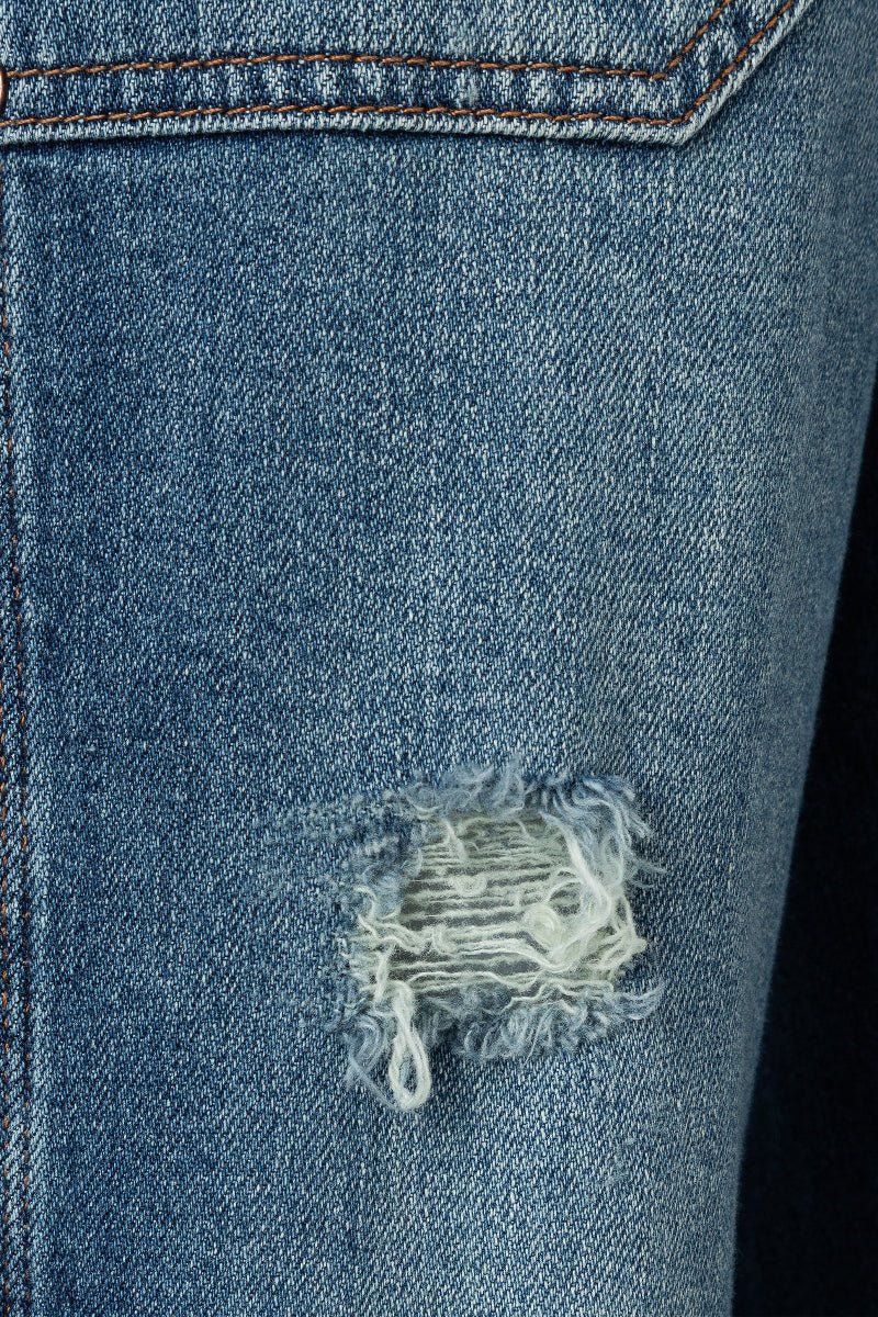 Close-up of a blue denim jacket with a distressed pocket detail.