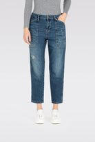 Person wearing blue jeans and a gray top on a white background