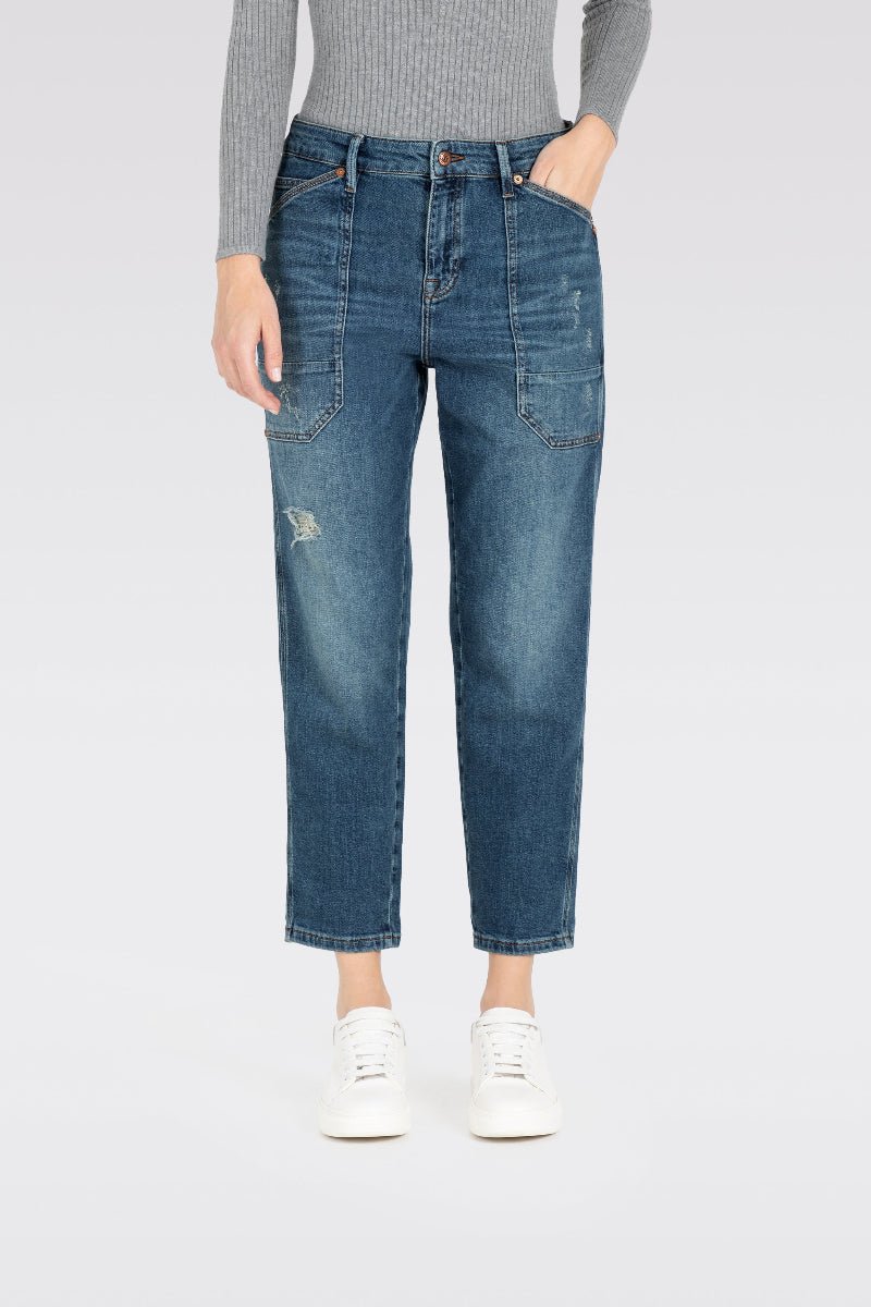 Person wearing blue jeans and a gray top on a white background