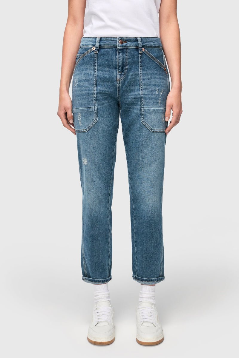 Person wearing blue jeans and white sneakers on a plain background