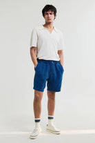 Person wearing a white polo shirt and blue shorts on a white background