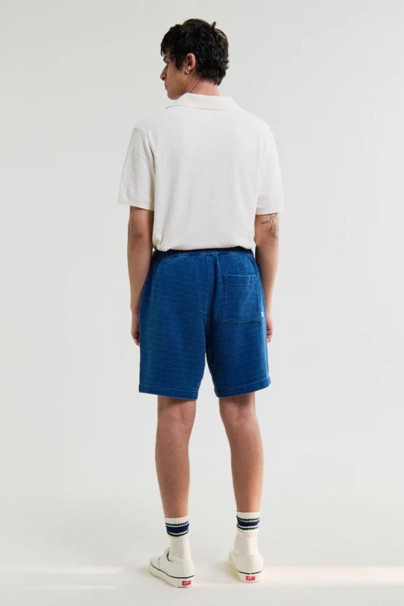 Person wearing a white t-shirt and blue shorts on a plain background