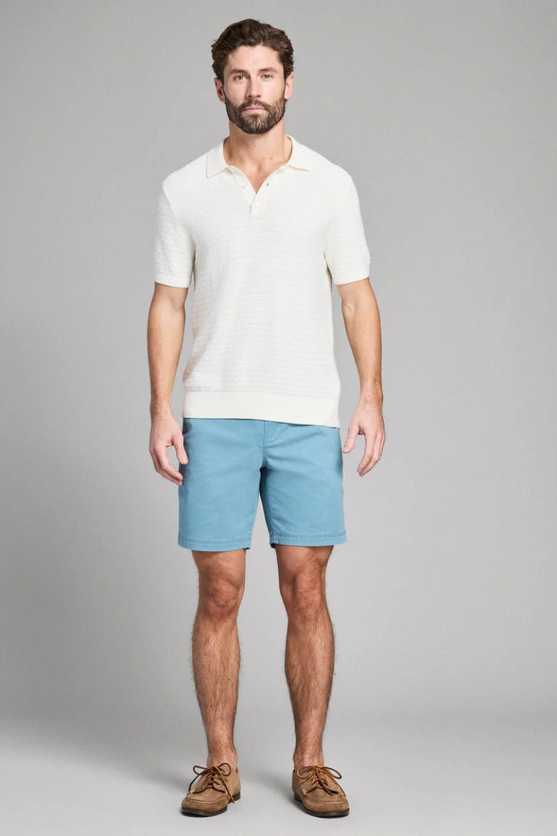 Man wearing a white shirt and blue shorts on a gray background