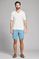 Man wearing a white shirt and blue shorts on a gray background