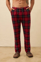 Person wearing red plaid pajama pants on a beige background