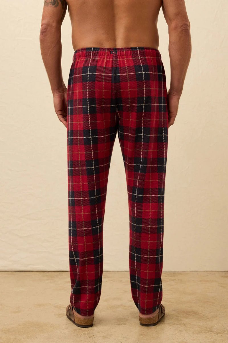 Red plaid pajama pants worn by a person on a beige background