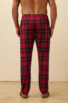 Red plaid pajama pants worn by a person on a beige background