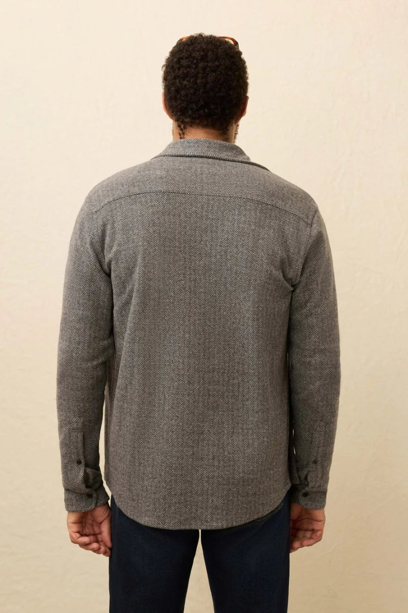 Person wearing a gray patterned shirt against a beige background