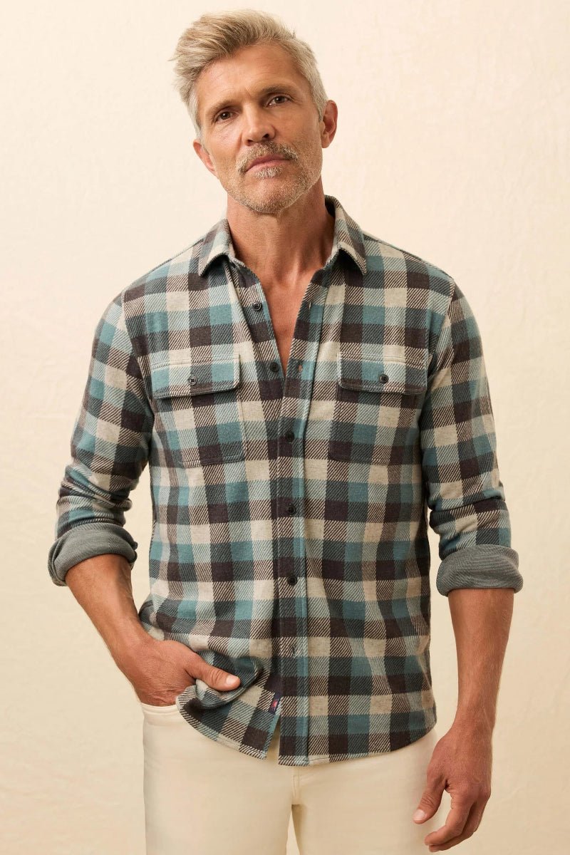 Man wearing a plaid shirt with rolled-up sleeves against a beige background