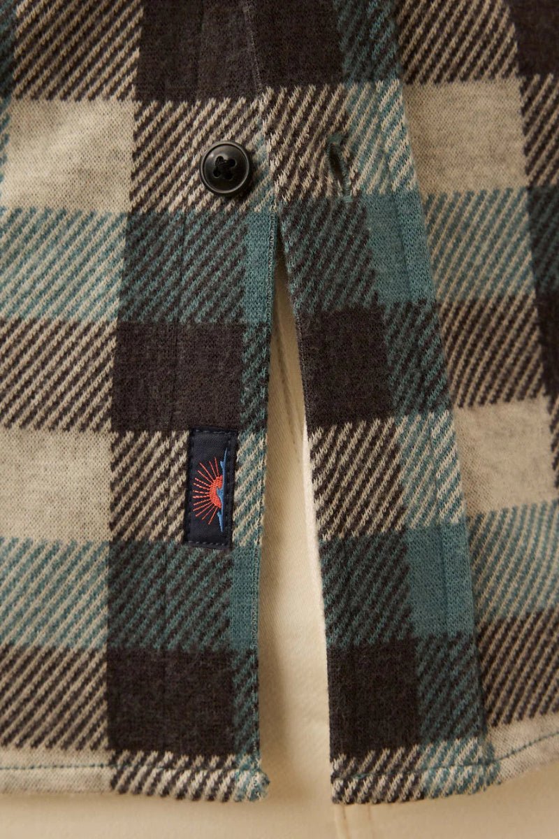 Close-up of a plaid fabric with a button and brand label.