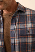 Close-up of a person wearing a plaid shirt with a neutral background