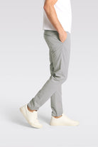 Person wearing light gray pants and white shoes on a plain background