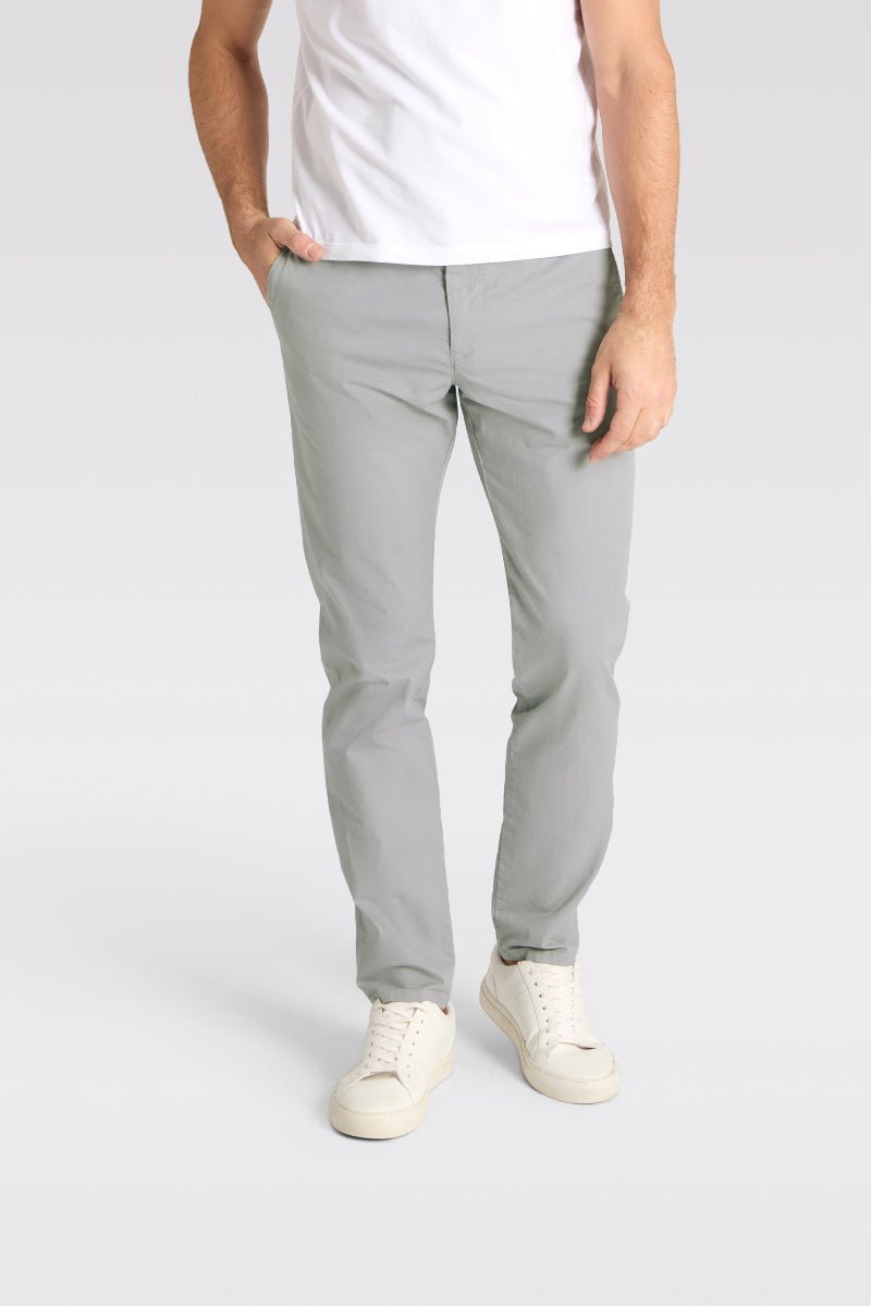 Person wearing light gray pants and white sneakers on a plain background