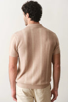 Man wearing a beige short-sleeve shirt against a white background