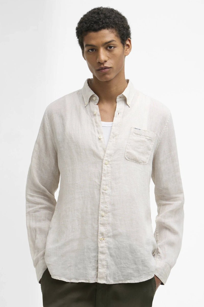 Man wearing a light-colored button-up shirt against a plain background