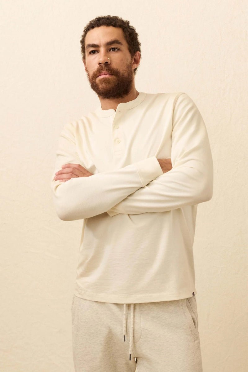 Man wearing a cream long-sleeve shirt and pants against a beige background