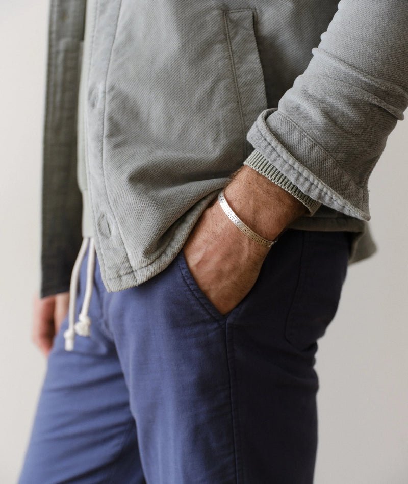 Person wearing a gray jacket and blue pants with a neutral background