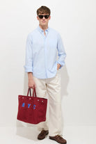 Man holding a red tote bag with 'NYC' letters against a white background