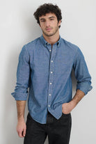 Man wearing a blue button-up shirt against a plain background