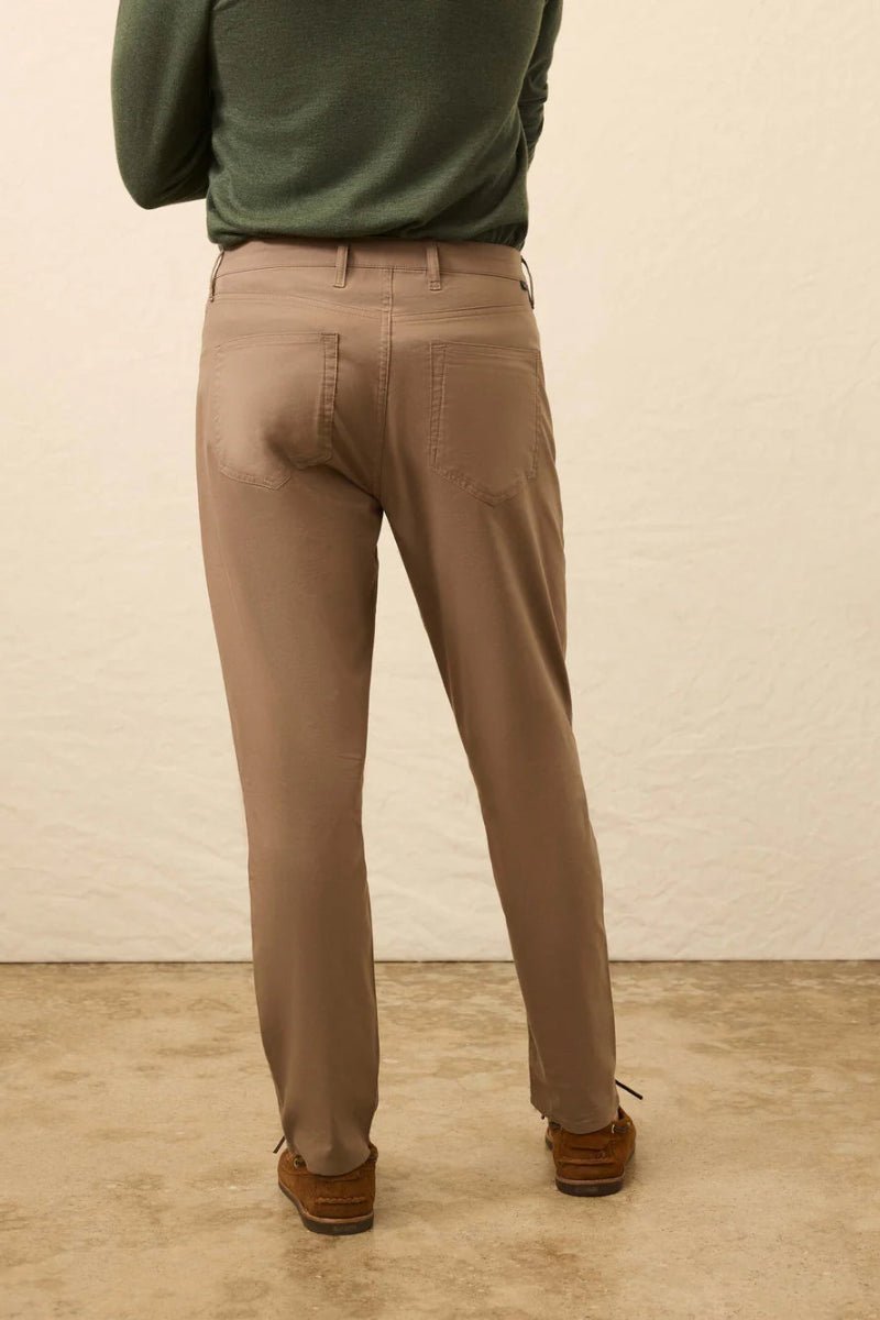 Person wearing beige pants and a green sweater against a plain background