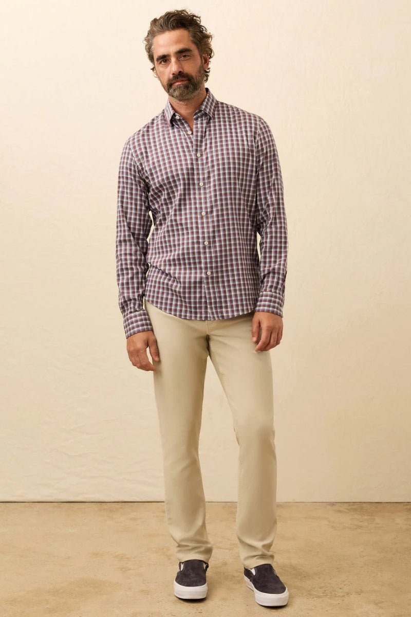 Man wearing a checkered shirt and beige pants against a plain background